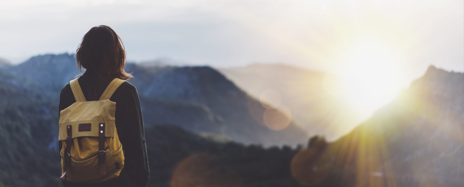 Woman overlooking sunset over the mountains